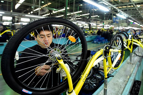A worker adjusts the parts of an ofo bicycle in a production plant of Flying Pigeon Cycle Development Co Ltd in Tianjin. The bicycle manufacturer has entered a partnership with the bike-sharing startup. (Photo/Xinhua)