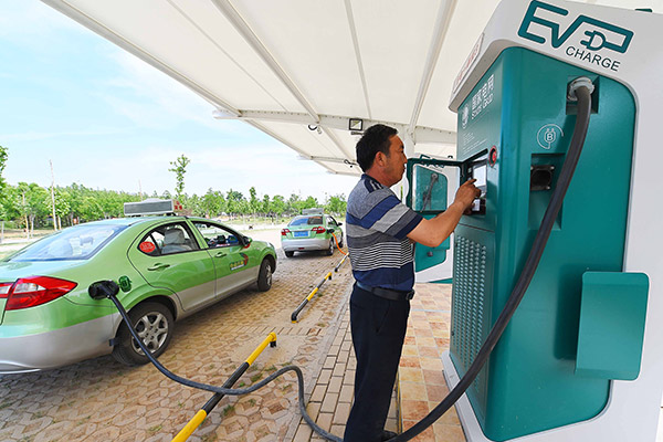 A taxi driver charges his electric car at a station in Weifang, Shandong province. (Photo/China Daily)