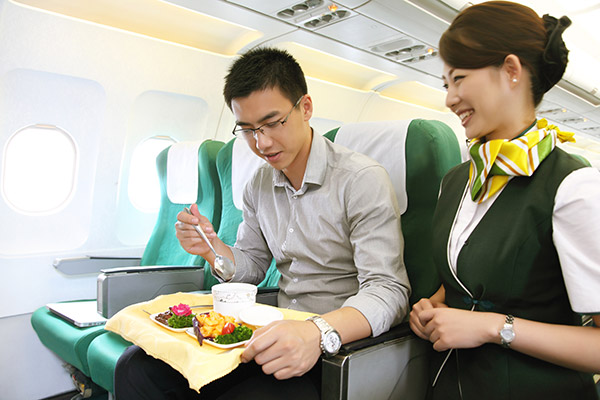 A Spring Airlines flight attendant serves a meal to a passenger in the 'Spring Plus' class, the business economy segment of the aircraft, during a flight. Spring Plus is the only class that offers food to fliers during flights of the budget airline. (Photo provided to China Daily)