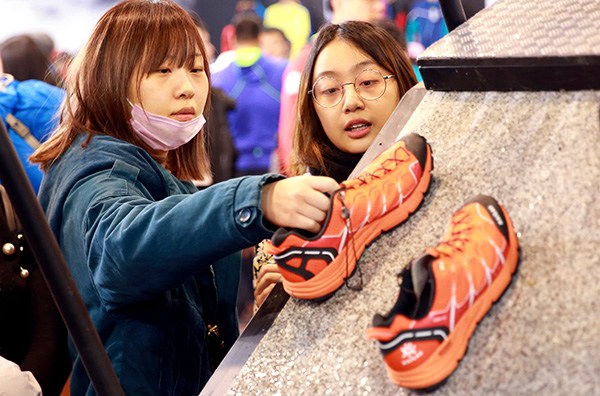 Visitors check shoes at the ISPO outdoor sports expo in Beijing in February. (Photo by Zou Hong/China Daily)