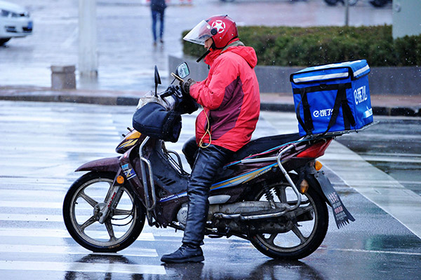 A food delivery man in Qingdao, Shandong province, checks his orders. (Photo/China Daily)