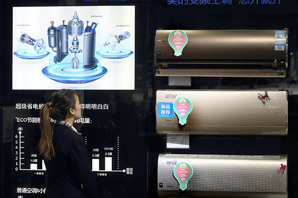 A customer looks at Midea's energy-efficient air conditioners at a store in Beijing. (Photo/China Daily)