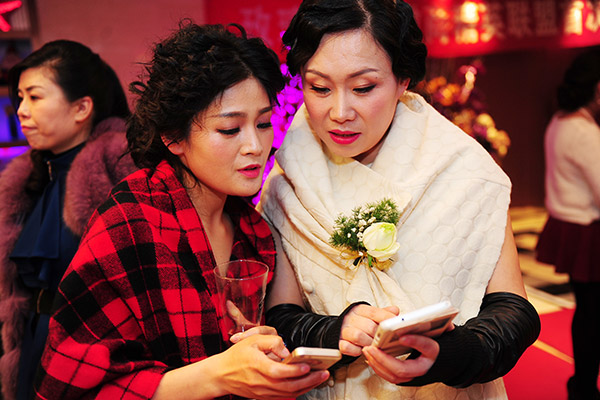 Two women business owners exchange contact details at a party for entrepreneurs to celebrate the International Women's Day on March 8, in Fuyang, Anhui province. (Photo/China Daily)