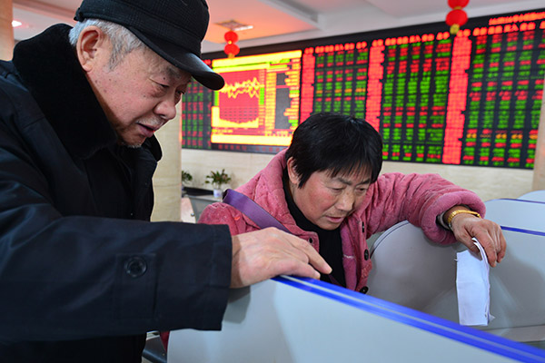 Investors check stock prices at a brokerage in Fuyang, Anhui province, on Wednesday. The pension funds' allocation to the stock market will be relatively low, according to Lou Jiwei, chairman of the National Council for Social Security Fund. (Photo/China Daily)