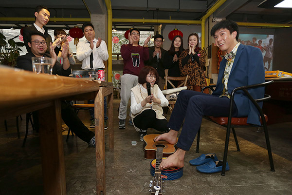Liu Tao, an armless singer, plays guitar with his toes for young professionals of a startup who reside at the You+ international apartment in Guangzhou. (Photo/China Daily)