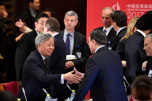 Asian Infrastructure Investment Bank (AIIB) President Jin Liqun (L) speaks with a guest during the China Development Forum (CDF) 2017 in Beijing, March 19, 2017. (Photo/Xinhua)