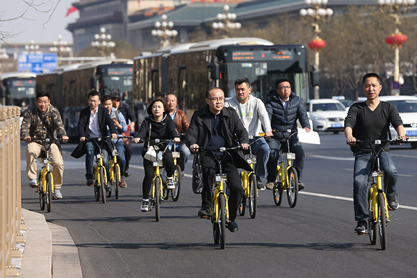 A group of bikers riding ofo bicycles pass by Chang'an Avenue, Beijing, on March 10, 2017. (Photo/China Daily)