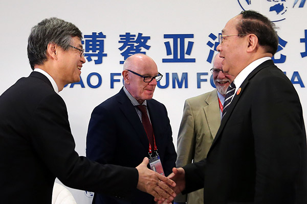 Li Ruogu (right), former chairman of the Export-Import Bank of China, shakes hands with Ryozo Himino, vice-minister for international affairs of the Financial Services Agency of Japan, after a seminar of the Boao Forum for Asia, March 24, 2017. (Photo/China Daily)