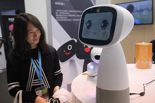 A visitor interacts with a robot at a high-tech exhibition in Shanghai. (CHEN YUYU/FOR CHINA DAILY)