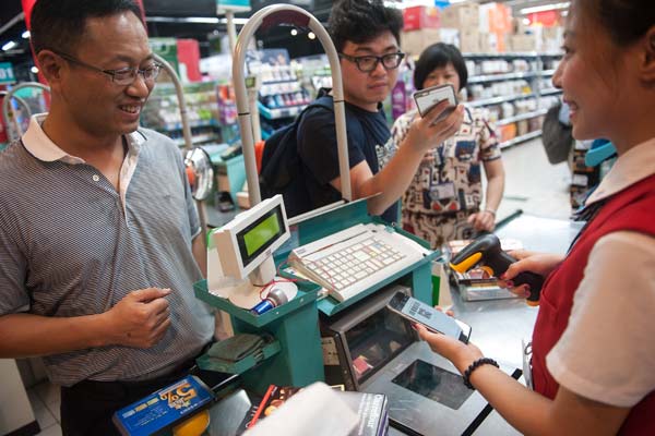 A cashier scans a buyer's WeChat Pay code on his mobile phone at a supermarket in Shenzhen, Guangdong province. (Photo provided to China Daily)