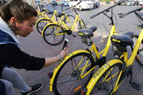 A rider in Qingdao, Shandong province, scans bar code for riding an ofo bike. (Photo by Huang Jiexian/For China Daily)