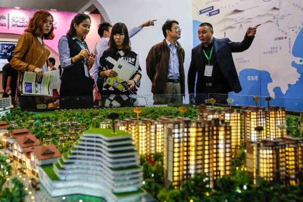Potential homebuyers look at a model of a new property project at a real estate expo in Beijing. (Photo by Kuang Linhua/China Daily)