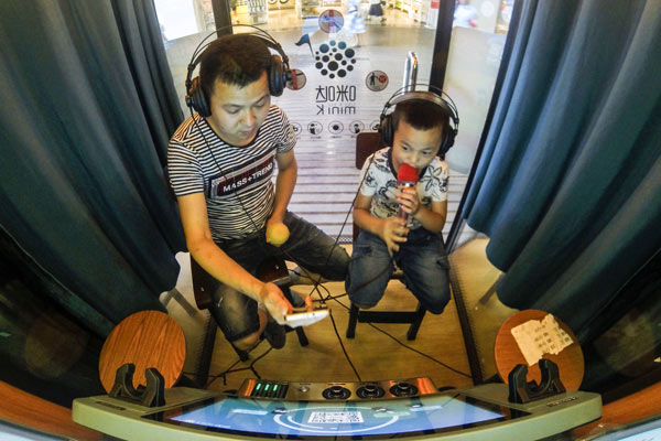 Customers sing at the mini karaoke booths in the basement of the Tianfu Square in Chengdu, capital of Sichuan province. There are four such mini booths here. It will cost 80 yuan ($11.6) for an hour of singing. (Photo by Hao Fei/For China Daily)