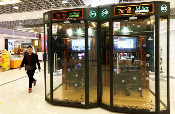 A man passes by two karaoke booths at Beijing Yintai Center in Beijing. (Photo by Feng Yongbin/China Daily)
