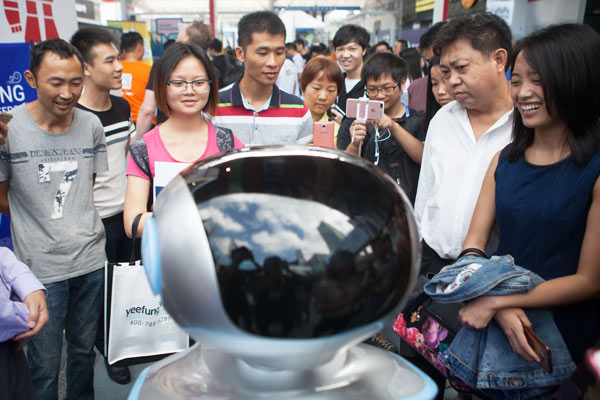 Visitors look at a robot at an innovation summit held in Guangzhou, capital of Guangdong province, which was sponsored by China Science and Merchants Investment Management Group. (Photo by Tan Qingju/China Daily)