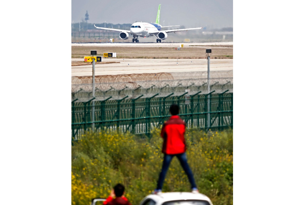 Fans watch C919, China's first homegrown big passenger jet, performing a high-speed taxiing test at the Pudong International Airport in Shanghai on Sunday. (Photo by Yin Liqin/For China Daily)