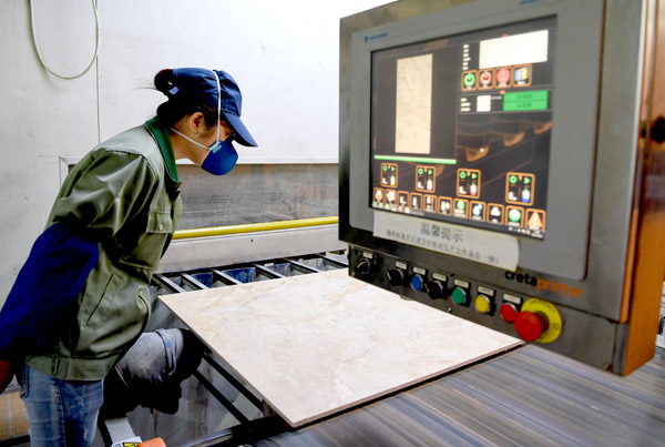 A worker observes the printing effect in the workshop of the Monalisa Group Co in Foshan, Guangdong province. XINHUA