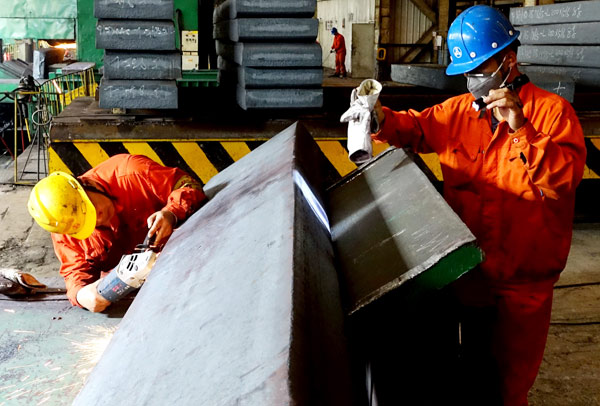 Workers examine the billet at a steel mill in Dalian, Liaoning province. LIU DEBIN / FOR CHINA DAILY