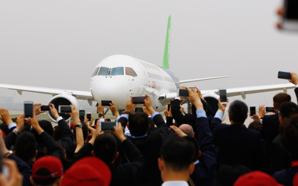 Guests vie to take photos of the C919 after its successful maiden test flight and landing at the Shanghai Pudong International Airport on Friday. FANG ZHE / XINHUA