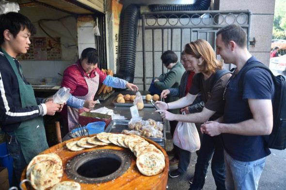 A foreigner scans the QR code to pay for snacks at a food stall in Hangzhou, the capital city of Zhejiang province, on April 14, 2017. (Photo/Xinhua)