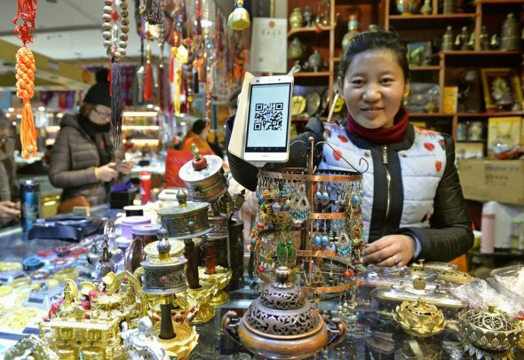A woman shows the QR code for mobile payment at her shop in Lhasa, Tibet autonomous region, on Jan 4, 2017. (Photo/Xinhua)