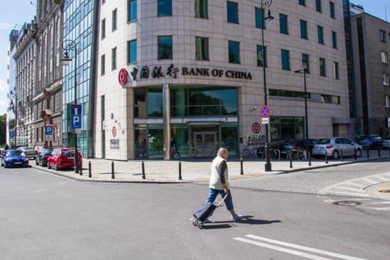 Photo taken shows a passerby walking in front of the Poland branch of the Bank of China in Warsaw, the countrys capital city. Officially started operation on June 6, 2012, the bank has had full access to the financial market of Poland, providing high-quality financial services for Chinese and Polish clients from the industrial, commercial and financial sectors as well as for individual customers. Its services include deposit, loan, remittance of local and foreign currencies, foreign exchange transactions, trade finance, and guarantee, etc. The branch is the first Chinese bank officially operating in Poland. (Photo by Xinhua News Agency)
