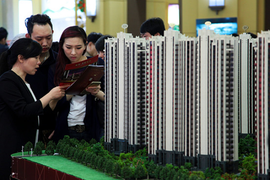 Prospective homebuyers at a realty expo in Shanghai check the fine-print of a marketing brochure for a modern housing estate. [Photo/China Daily]