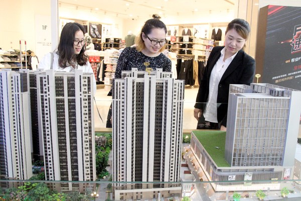 A representative of a real estate developer in Suzhou promotes an upcoming project to prospective buyers at a shopping mall, where a model of the property was kept on display at an industry event. WANG JIANKANG / FOR CHINA DAILY