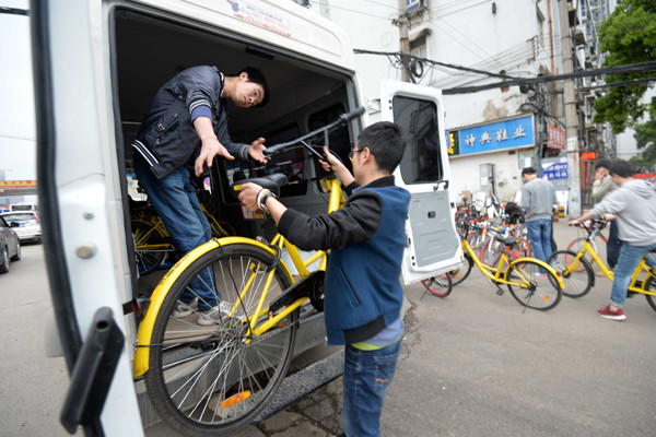 Employees of a bike-sharing company clear bicycles that users improperly parked on a street near Optics Valley Square in Wuhan, Hubei province, in April.(Photo/Xinhua)