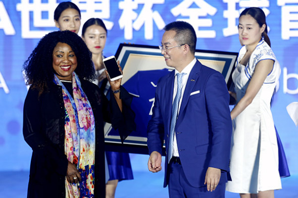 FIFA Secretary-General Fatma Samoura displays a Vivo smartphone presented to her by Ni Xudong, senior vice-president of Vivo Mobile Communication Technology Co Ltd, in Beijing on Wednesday. (Photo/China News Service)