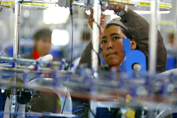 A worker fixes a thread on the production line at Huafu Top Dyed Melange Yarn Co in Aksu, a southern city in the Xinjiang Uygur autonomous region. Photo By Zhu Xingxin / China Daily