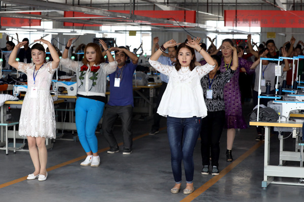 Workers dance during a break at a textile factory in Aksu. Photo By Zhu Xingxin / China Daily