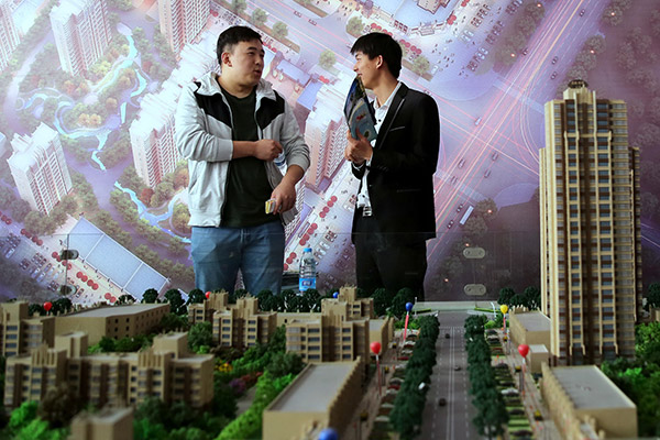 A prospective homebuyer enquires about a new project at a property event in Hebei's Handan. Some listed small and mid-sized real estate companies have been facing difficulties in home sales in third-and fourth-tier cities after stricter norms took effect last month. (Photo provided to China Daily)