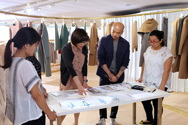 Wang Zhen (second from left), founder and president of 1436, discusses sketches for the styles of the new fashion season with other designers at the company's Beijing office in 2015. (Photo provided to China Daily)