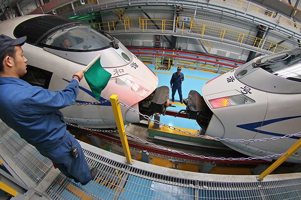 A worker guides two bullet trains to connect at a CRRC plant in Qingdao, Shandong province. CRRC hopes to take a 10 to 15 percent global market share by 2020. (Photo/China Daily)