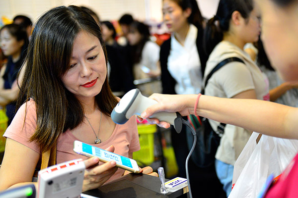 A woman uses Alipay, a business of Ant Financial, via her mobile phone at a store in Singapore. (Photo/Xinhua)