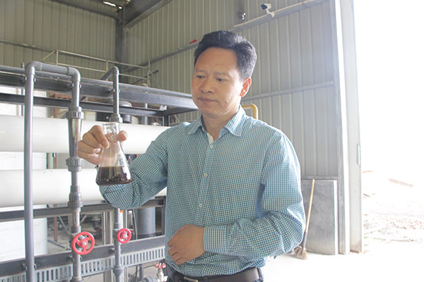 Zhu Youbiao, founder of Kaiqi Energy Technology Co Ltd, shows the brown liquid fertilizer made from pigs' excretions. (Photo/China Daily)