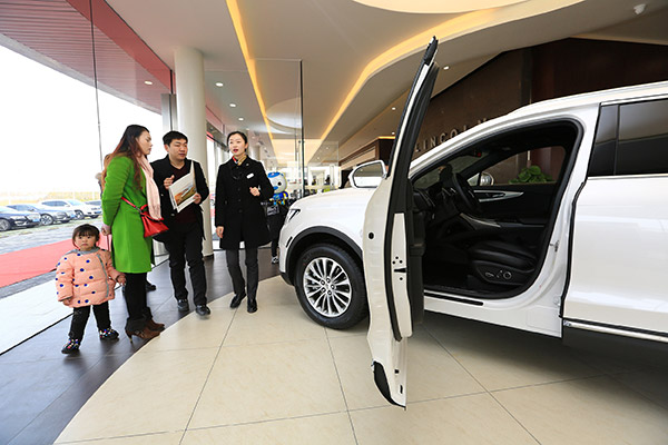 A family in Xiangyang, Hubei province, listen to the car sales personnel's introduction at a dealership in January. (Photo/China Daily)