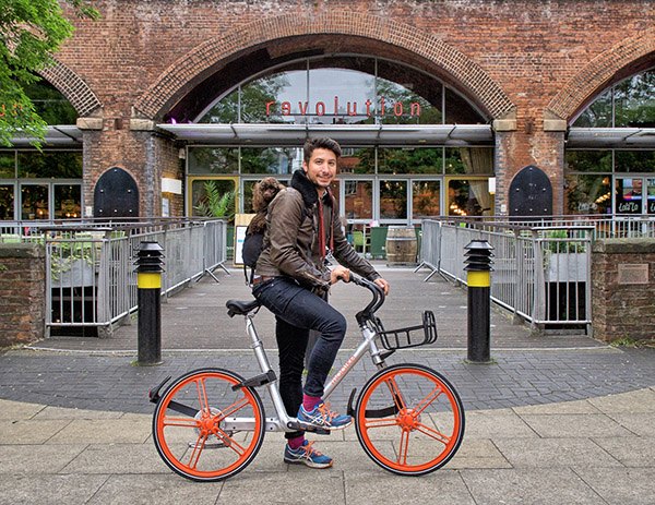 A cyclist tries bike-sharing company Mobike's new orange bike in Manchester. (Photo/provided to chinadaily.com.cn)
