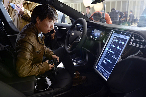 People experience Tesla's new product in 2015. The company has been developing autonomous cars in recent years. (Photo/Xinhua)