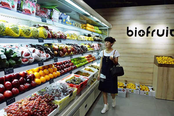 A woman selects fruits at an imported food store in Hangzhou, Zhejiang province. (Photo/China Daily)