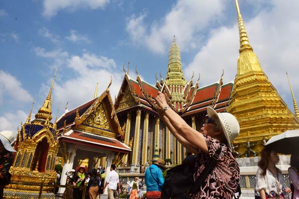 A Chinese tourist takes a photo at a Buddhist temple in Bangkok. (Photo/China Daily)