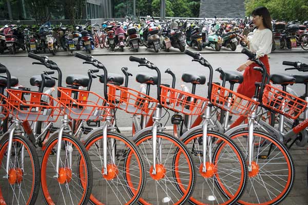 A woman walks past Mobikes lined up in a street in Zhengzhou, capital of Henan province. (Photo/China Daily)
