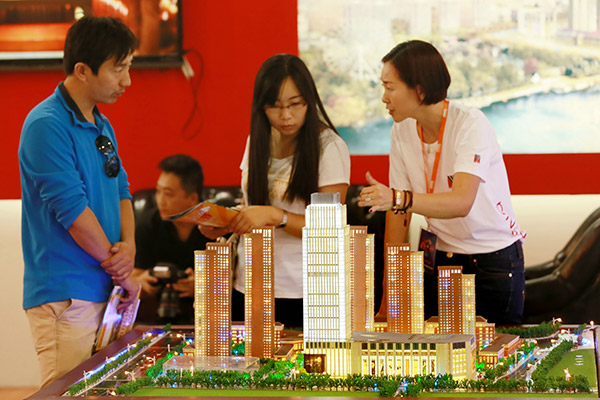 Prospective homebuyers enquire about an upcoming residential property at a Beijing real estate fair. Recent measures against speculative property investments are said to be pushing demand from top-tier cities to small cities. (Photo provided to China Daily)