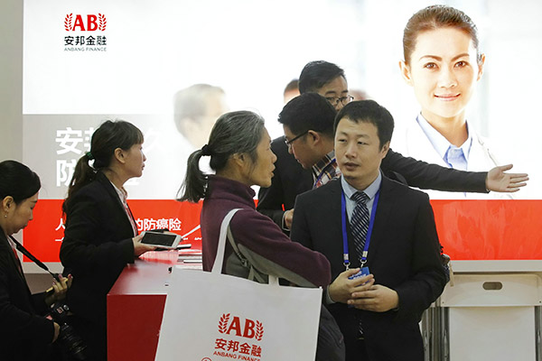 Anbang sales staff explain the insurer's products to visitors at the Beijing Internatonal Investment and Wealth Management Expo. (Photo/China Daily)