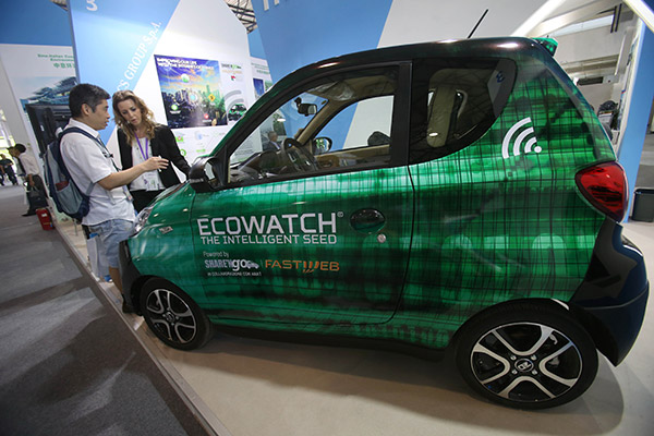A worker introduces an electric model designed in Italy and produced in China to a visitor at the 15th China International Environmental Protection Exhibition Conference in Beijing. (Photo/China Daily)