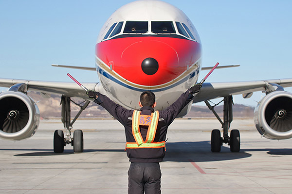 A ground crew member leads a China Eastern Airlines cargo plane to land at Yantai Penglai International Airport in Shandong province. (Photo/China Daily)