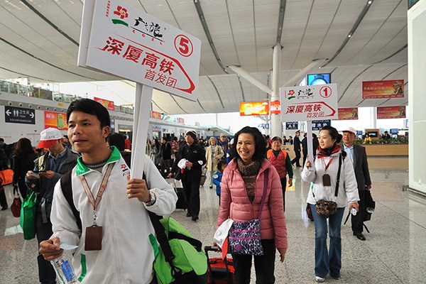 A tour guide from GZL leads a group of tourists to take the first high-speed train connecting Shenzhen in Guangdong province and Xiamen in Fujian province. (Photo/China Daily)