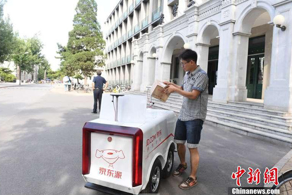 A student picks up a delivery from a JD.com robot courier at Renmin University in Beijing on June 18. (Photo/Chinanews.com)