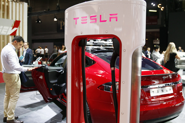 A Tesla electric charger is displayed next to a Telsa model S car during an auto show in Paris, France. (Photo provided to CHINA DAILY)